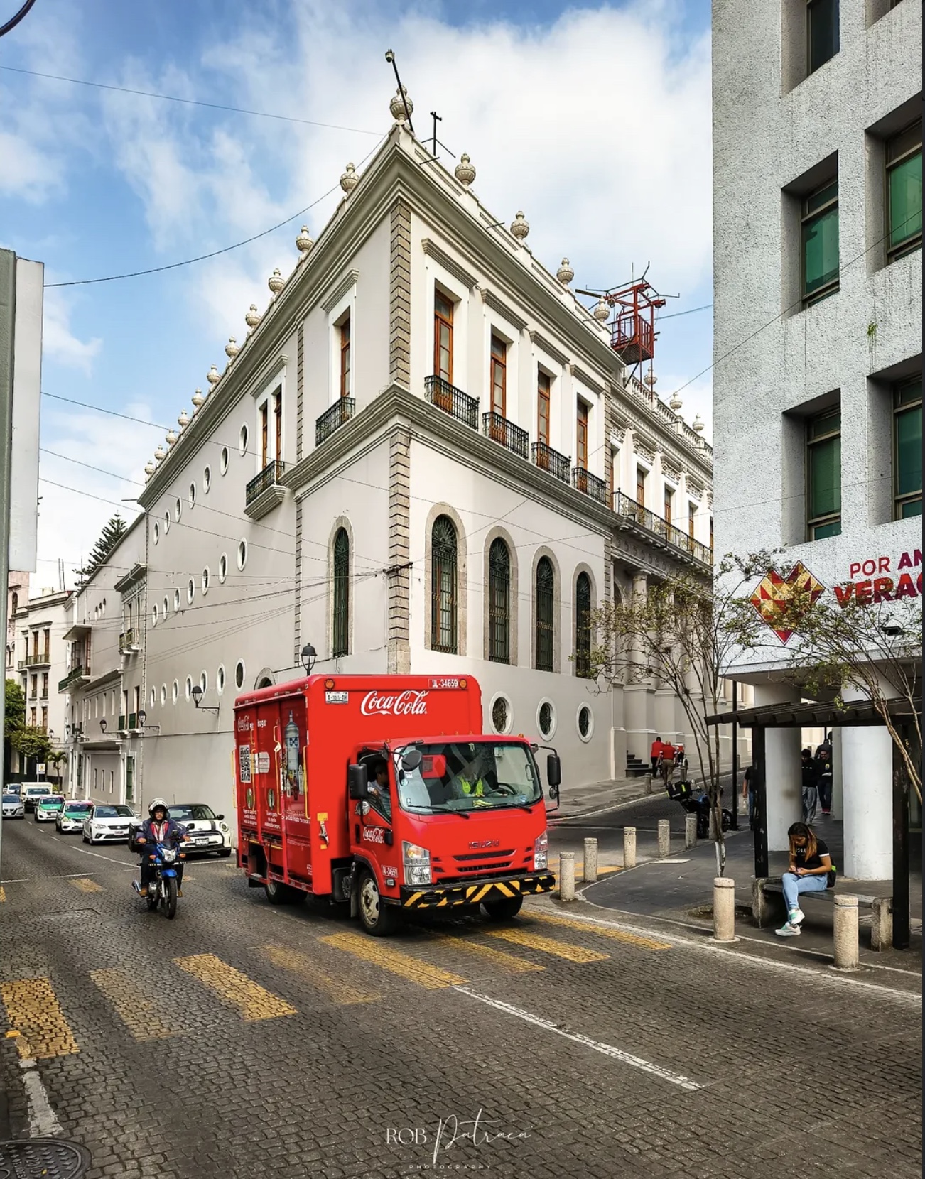 Edificio colonial en calle empedrada con camión de reparto de Coca-Cola